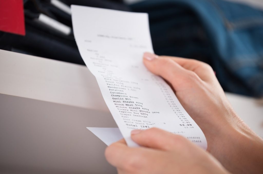 A customer holding a receipt from a working POS system in a store